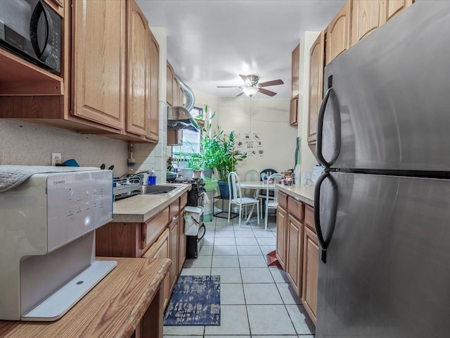 kitchen featuring freestanding refrigerator, black microwave, a ceiling fan, light countertops, and light tile patterned flooring