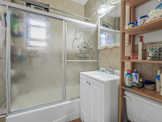 full bathroom with toilet, vanity, tile walls, and bath / shower combo with glass door