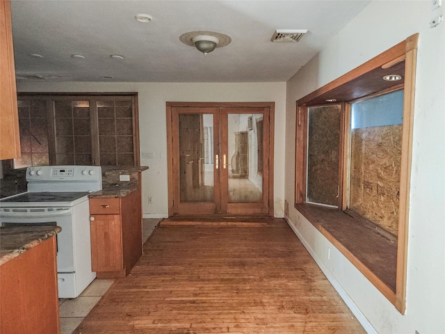 144 Union Ave, Patchogue, NY 11772 - kitchen featuring white electric range oven, light wood-style flooring, brown cabinetry, and dark countertops