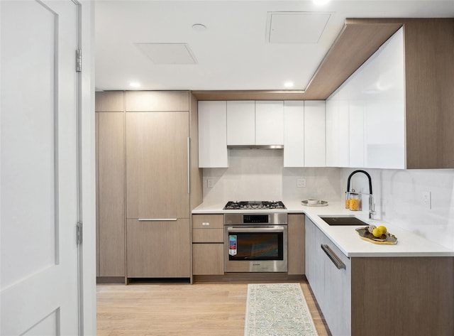 kitchen featuring stainless steel appliances, a sink, modern cabinets, white cabinets, and recessed lighting