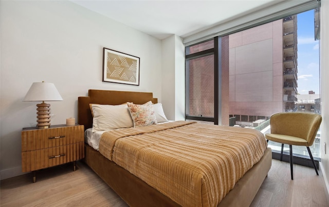 bedroom featuring light wood-type flooring and expansive windows