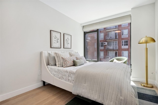 bedroom with wood finished floors, baseboards, and floor to ceiling windows