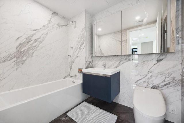 bathroom with tile walls, toilet, vanity, and shower / tub combination