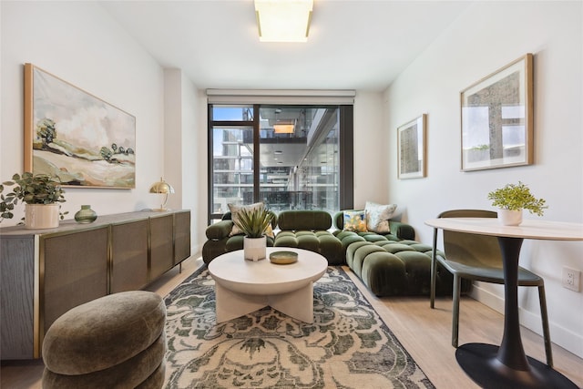sitting room featuring light wood-style flooring, baseboards, and a wall of windows