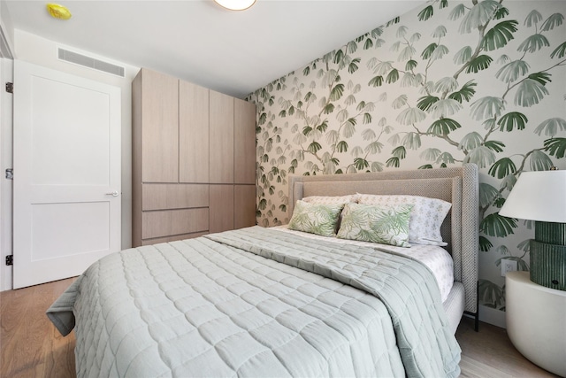 bedroom with wallpapered walls and wood finished floors