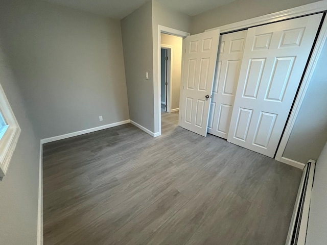 57 Doud St, Farmingdale, NY 11735 - unfurnished bedroom with wood finished floors, baseboards, a closet, and baseboard heating