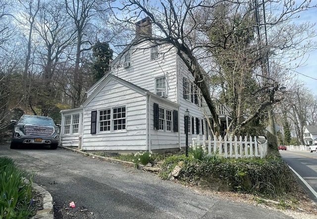 view of side of home featuring a chimney and fence