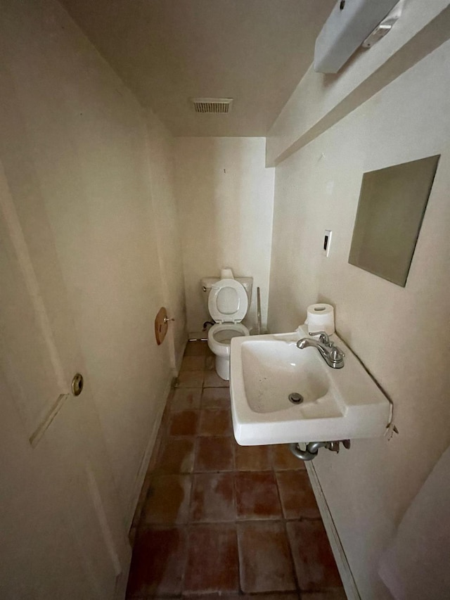 half bathroom with a sink, tile patterned flooring, toilet, and baseboards