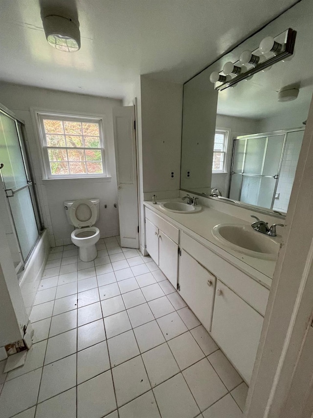 bathroom with tile patterned floors, double vanity, toilet, and combined bath / shower with glass door