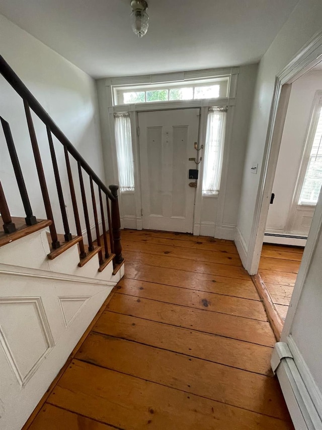 entrance foyer with light wood-style floors, a baseboard heating unit, stairs, and baseboards