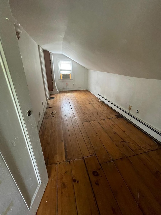 additional living space featuring vaulted ceiling, light wood finished floors, a baseboard radiator, and cooling unit