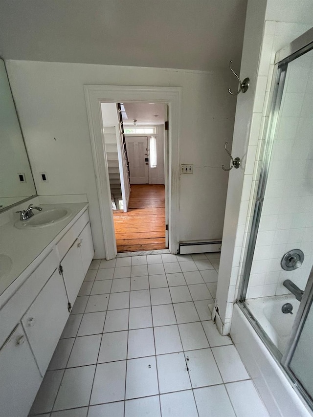 bathroom featuring a baseboard heating unit, tile patterned floors, shower / bath combination with glass door, and double vanity