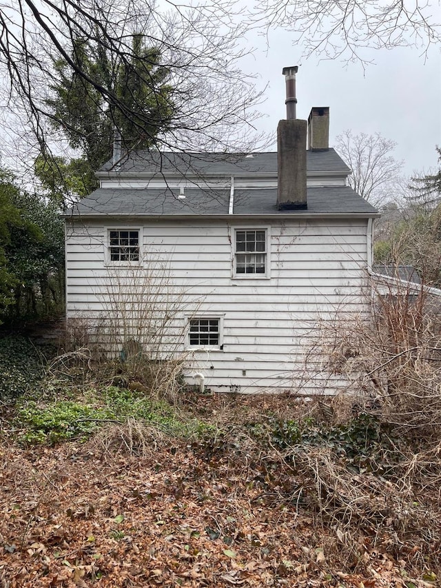 view of property exterior featuring a chimney and roof with shingles