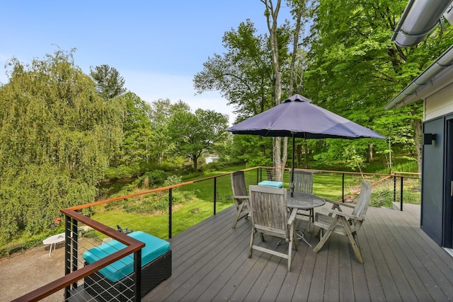 wooden deck featuring outdoor dining area and a lawn