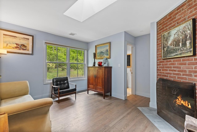 living area with wood finished floors, a skylight, baseboards, and a fireplace