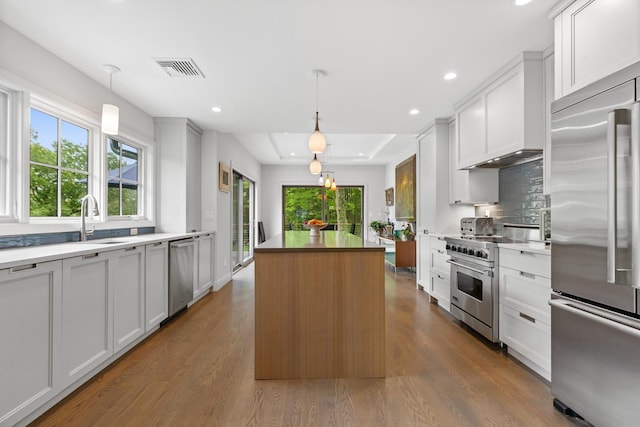kitchen with stainless steel appliances, a kitchen island, decorative backsplash, wood finished floors, and recessed lighting