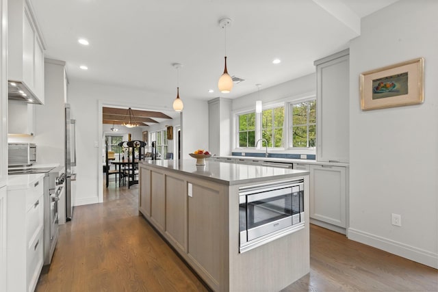 kitchen with stainless steel appliances, a center island, dark wood-type flooring, recessed lighting, and baseboards