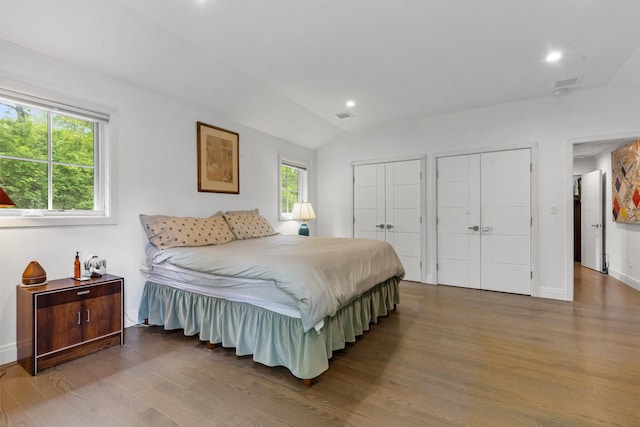 bedroom featuring vaulted ceiling, multiple closets, wood finished floors, baseboards, and recessed lighting
