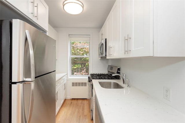 1 Hawley Ter Unit 5E, Yonkers, NY 10701 - kitchen featuring appliances with stainless steel finishes, radiator, white cabinets, a sink, and light stone counters