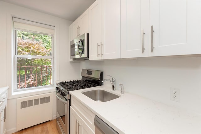 1 Hawley Ter Unit 5E, Yonkers, NY 10701 - kitchen featuring stainless steel appliances, radiator, a sink, white cabinets, and light stone counters