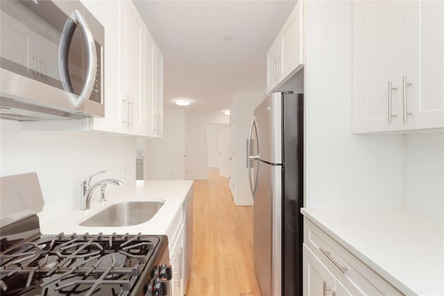 1 Hawley Ter Unit 5E, Yonkers, NY 10701 - kitchen featuring appliances with stainless steel finishes, a sink, light wood finished floors, white cabinets, and light stone countertops
