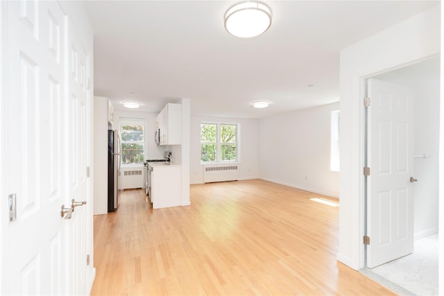 1 Hawley Ter Unit 5E, Yonkers, NY 10701 - unfurnished living room featuring radiator, light wood finished floors, and baseboards