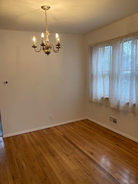 16615 67th Ave, Fresh Meadows, NY 11365 - spare room with a chandelier, wood finished floors, and baseboards
