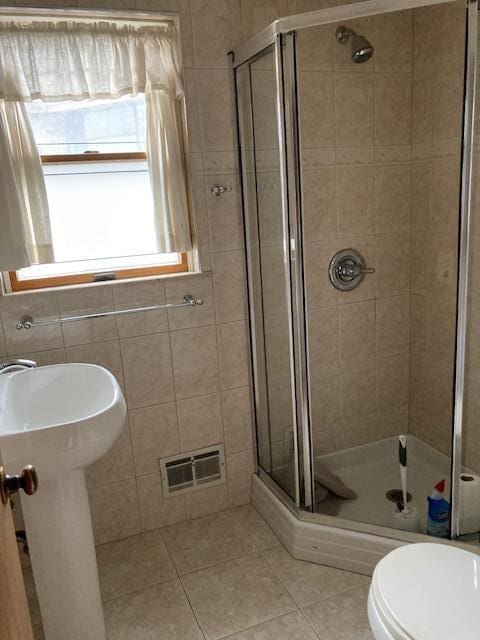 16615 67th Ave, Fresh Meadows, NY 11365 - full bath with tile patterned floors, a shower stall, toilet, a sink, and tile walls