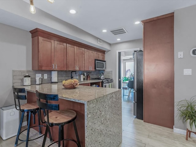 12 Deepwater Way Unit 31, Bronx, NY 10464 - kitchen with stainless steel appliances, tasteful backsplash, a peninsula, light stone countertops, and light wood-style flooring