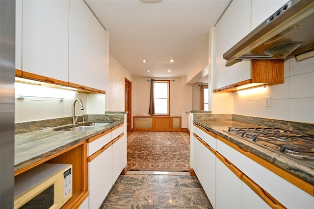 kitchen with white microwave, under cabinet range hood, a sink, white cabinets, and recessed lighting