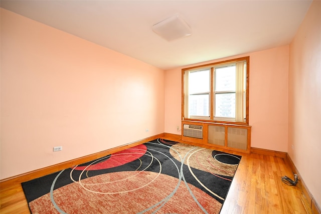spare room with wood finished floors, baseboards, and an AC wall unit
