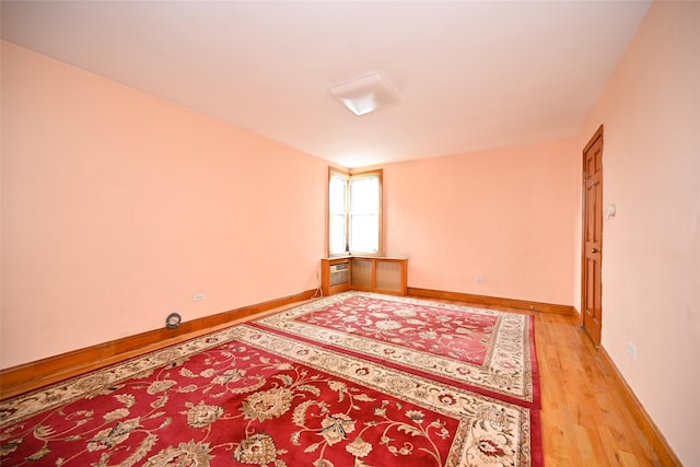 spare room featuring light wood-style floors, baseboards, and an AC wall unit