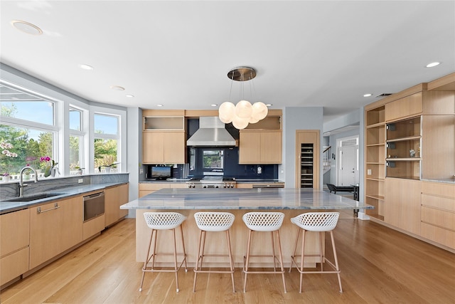 14 S Country Rd, Westhampton, NY 11977 - kitchen with wall chimney range hood, light brown cabinets, modern cabinets, stone countertops, and light wood-style floors