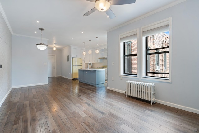 89-10 35th Ave Unit F2L, Jackson Heights, NY 11372 - unfurnished living room with radiator, crown molding, ceiling fan, a sink, and dark wood finished floors