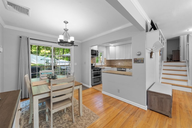 10 Ridge Rd, Cortlandt Manor, NY 10567 - dining room with a chandelier, light wood-style floors, healthy amount of natural light, stairs, and crown molding