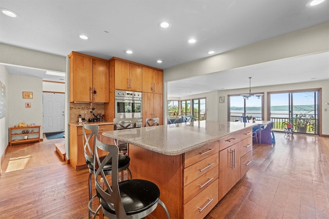 1260 Albany Post Rd, Croton-On-Hudson, NY 10520 - kitchen featuring oven, hardwood / wood-style floors, recessed lighting, light stone counters, and a center island