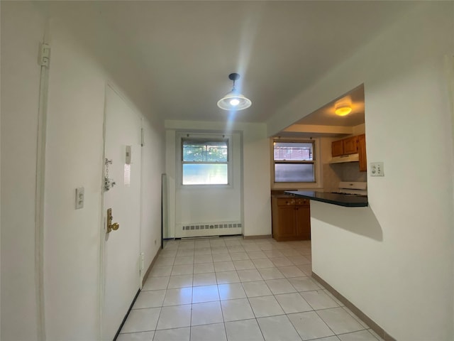 98-05 63rd Rd Unit 1C, Rego Park, NY 11374 - kitchen featuring a baseboard heating unit, brown cabinets, under cabinet range hood, dark countertops, and baseboards