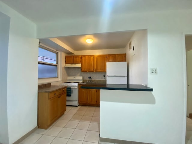 98-05 63rd Rd Unit 1C, Rego Park, NY 11374 - kitchen with white appliances, under cabinet range hood, light tile patterned floors, dark countertops, and brown cabinets