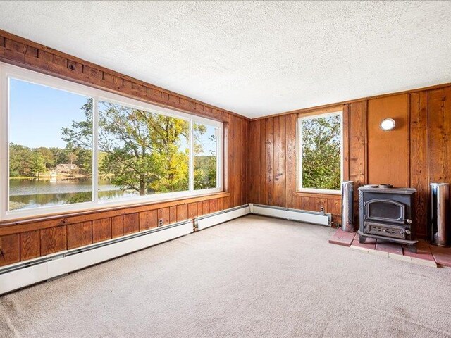 58 Hathorn Blvd, Port Jervis, NY 12771 - unfurnished living room with a wood stove, carpet flooring, healthy amount of natural light, a water view, and a textured ceiling