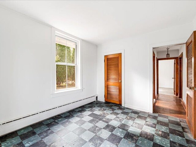 58 Hathorn Blvd, Port Jervis, NY 12771 - unfurnished bedroom featuring a baseboard heating unit, dark floors, baseboards, and a closet