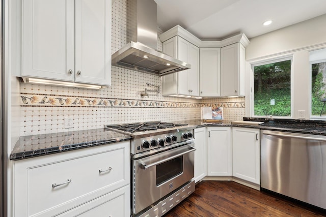 56 Rolling Way, New Rochelle, NY 10804 - kitchen with wall chimney exhaust hood, appliances with stainless steel finishes, decorative backsplash, dark wood-type flooring, and dark stone counters