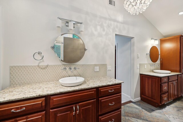 56 Rolling Way, New Rochelle, NY 10804 - bathroom with lofted ceiling, decorative backsplash, two vanities, stone tile flooring, and baseboards