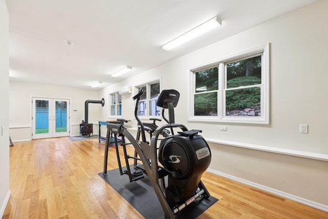 56 Rolling Way, New Rochelle, NY 10804 - exercise area with a wood stove, french doors, a wall mounted air conditioner, wood finished floors, and baseboards