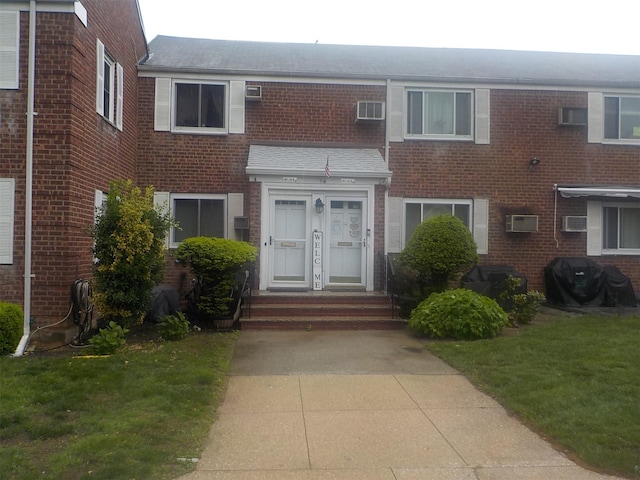 261-34 Langston Ave Unit E-2, Glen Oaks, NY 11004 - view of property featuring brick siding, a wall unit AC, and a shingled roof