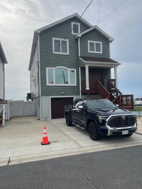 view of front facade featuring driveway, a garage, and fence