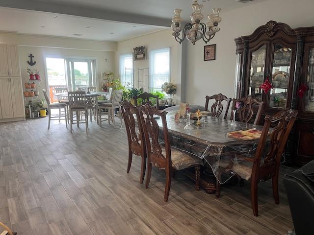 dining area with light wood finished floors, plenty of natural light, and a chandelier