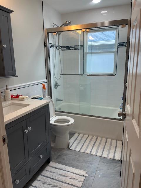 full bath with vanity, enclosed tub / shower combo, and toilet