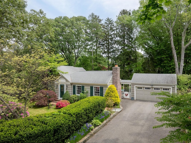 23 Severin Pl, Huntington, NY 11743 - view of front facade featuring driveway, a chimney, a garage, and view of wooded area