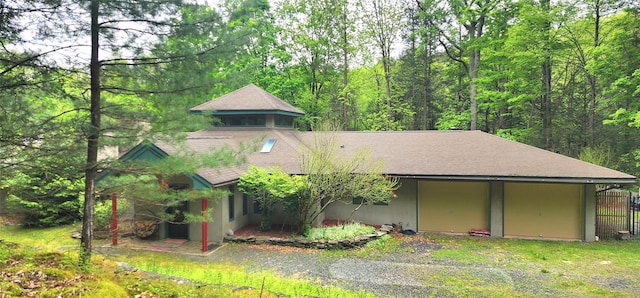 view of front of house with a shingled roof and a forest view