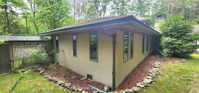 view of property exterior with stucco siding, a chimney, and fence
